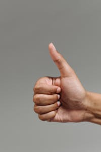 A close-up of a hand showing a thumbs up gesture, symbolizing success and approval.